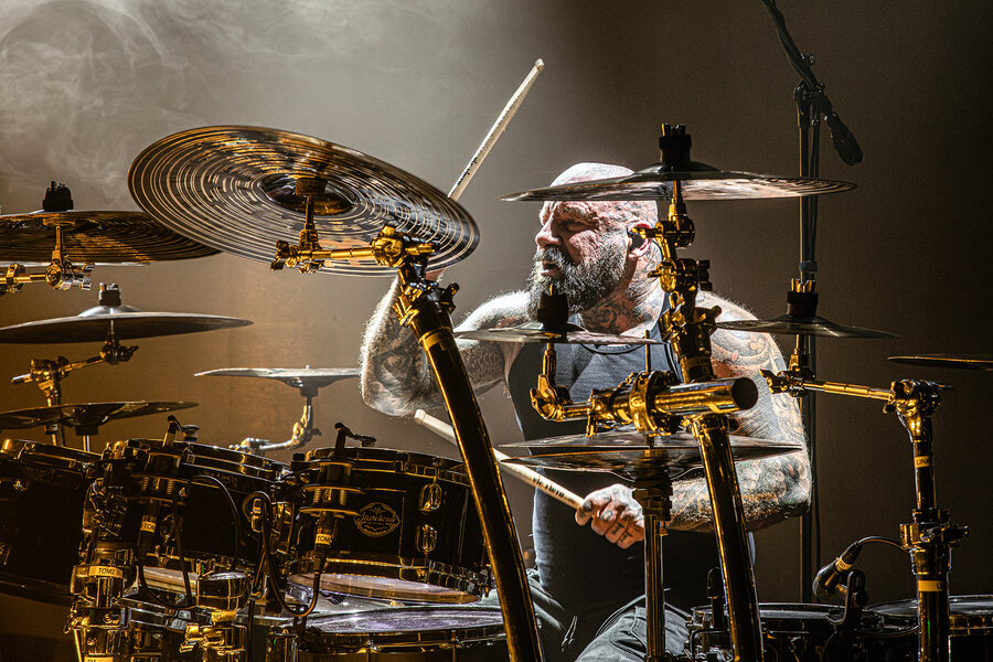 Schlagzeuger Vic Chains von Remode hinter seinem goldenen Custom-Drumkit, fotografiert durch die Becken hindurch